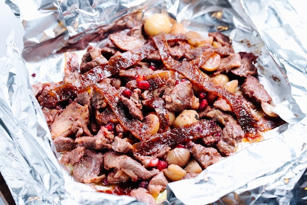 mushroom and meat slices in pot topped with pomegranate