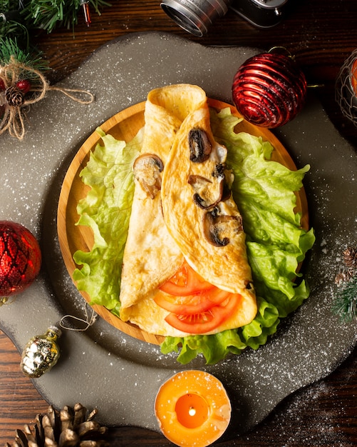 Mushroom omelette placed on lettuce and wrapped around tomato slices
