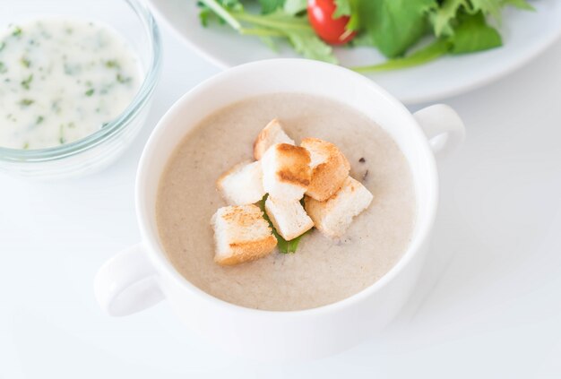 Zuppa di funghi e pane in tazza di ceramica bianca