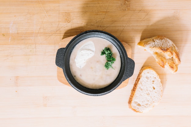 Mushroom soup with bread slices on wooden textured background