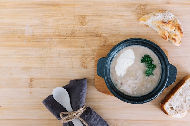 Mushroom soup with bread; tablecloth and spoon on wooden backdrop