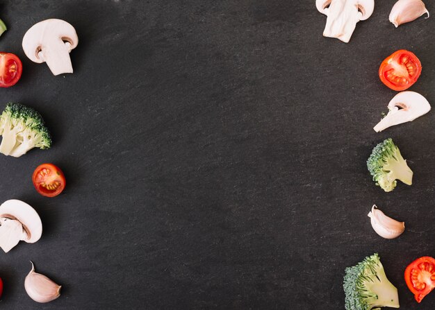 Mushroom; tomatoes; broccoli and garlic cloves on black background with space for writing the text