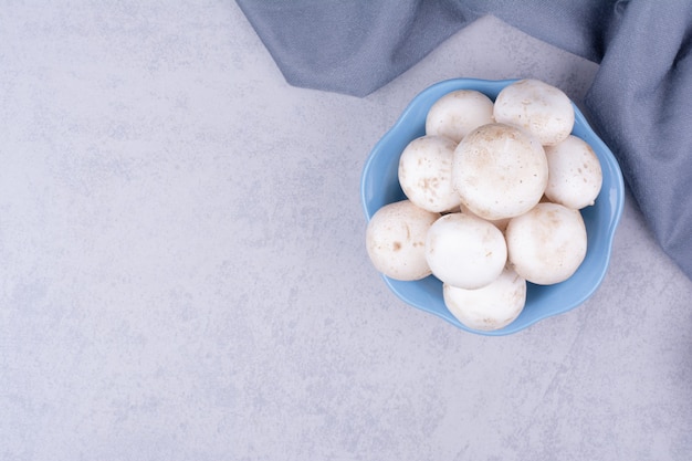 Mushrooms in a blue cup on grey surface