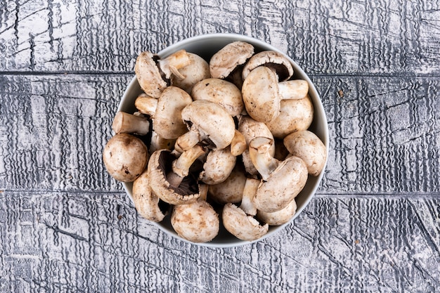 Mushrooms in a bowl flat lay on a gray wooden table