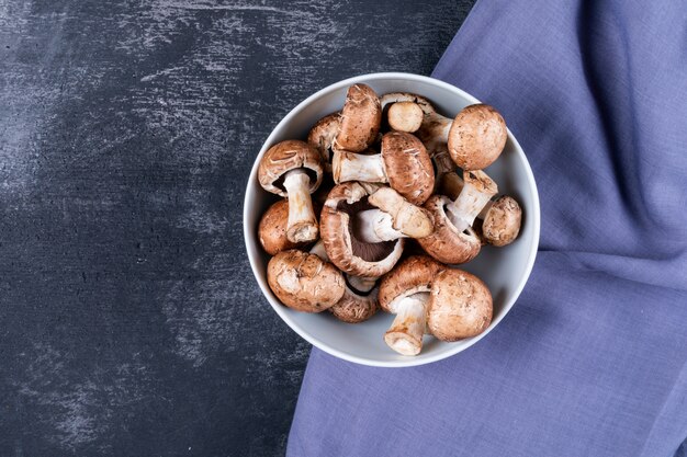 Mushrooms in a bowl on purple cloth on a dark table