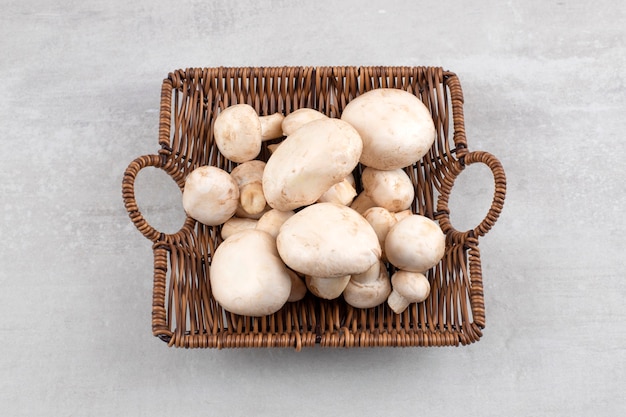 Mushrooms in a wicker basket, on the marble table. 