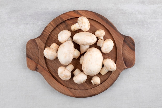 Mushrooms on a wooden plate, on the marble table. 