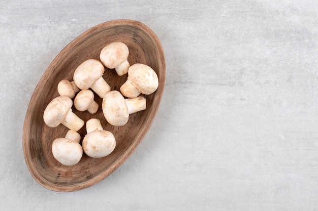 Mushrooms on a wooden plate, on the marble table. 