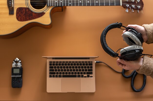 Music background with headphones in female hands recorder laptop and guitar