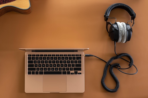 Music background with headphones laptop and guitar flat lay