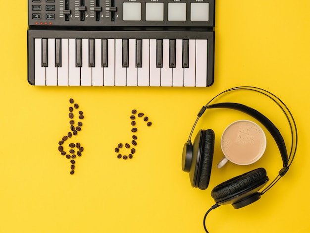 黄色​の​背景​に​音楽​ミキサー​、​コーヒー​豆​の​ノート​と​ヘッド​フォン​。​音楽​を​書く​という​概念​。​音楽​トラック​を​録音する​ため​の​機器​。​上​から​の​眺め​。​フラット​レイ​。