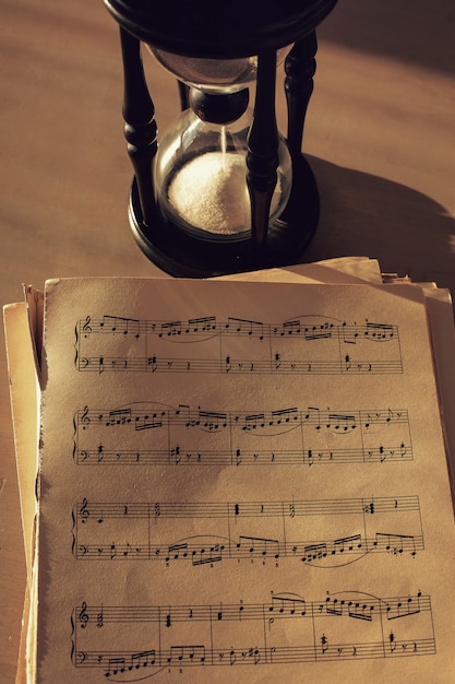 Free photo music notes on papers and hourglass