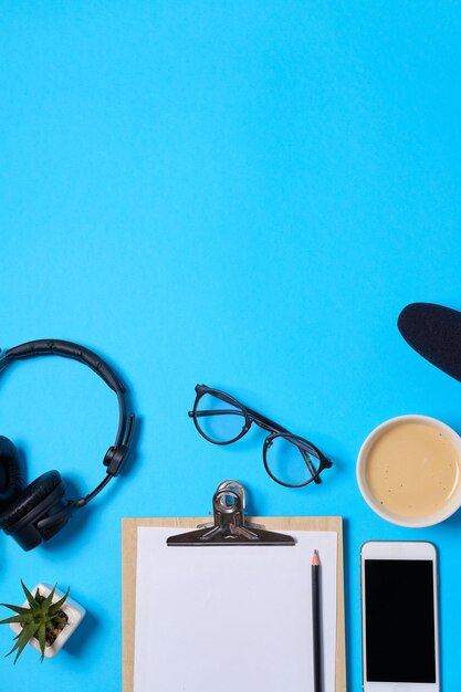 Музыкальный или подкастовый фон с наушниками, микрофоном, кофе и пустым на синем столе плоской планировкой Вид сверху плоской планировки