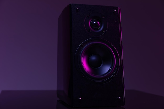 Музыкальный динамик из домашнего кинотеатра на темном фоне с фиолетовой подсветкой музыкальной индустрии