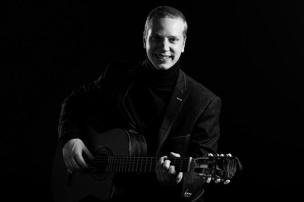 Music. Young musician in black suit holding a guitar