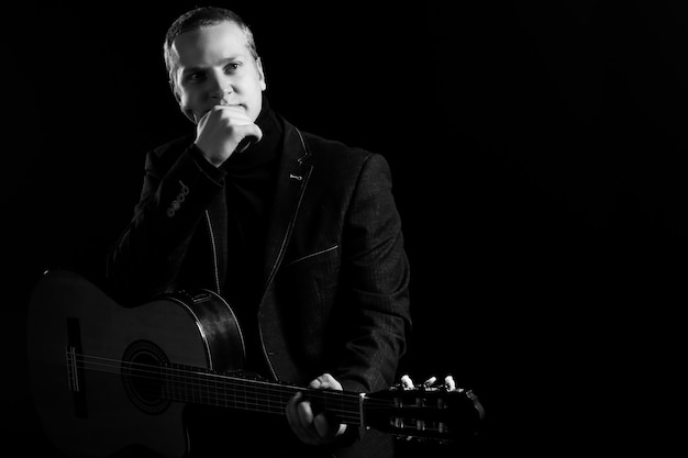 Free photo music. young musician in black suit holding a guitar