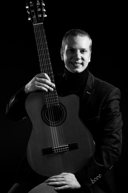 Music. Young musician in black suit holding a guitar