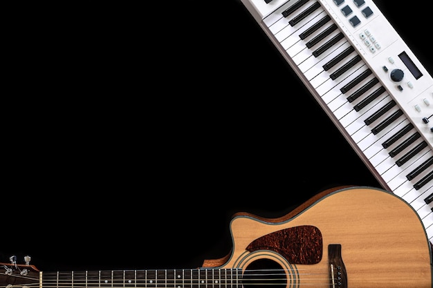 Free photo musical background with acoustic guitar and musical keys on black copy space