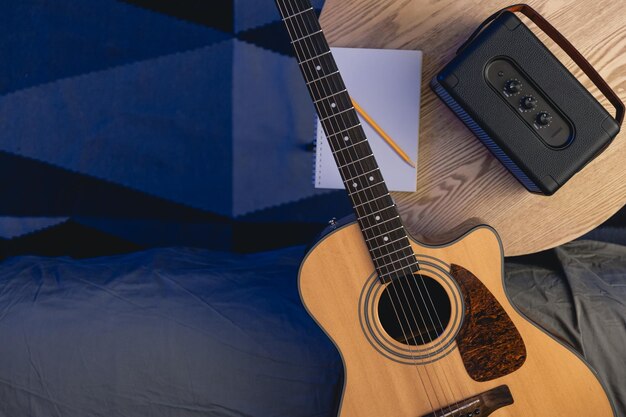 Musical background with acoustic guitar speaker and notepad on the table