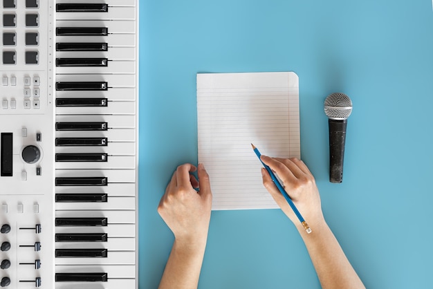 Musical keys microphone and blank paper on a blue background