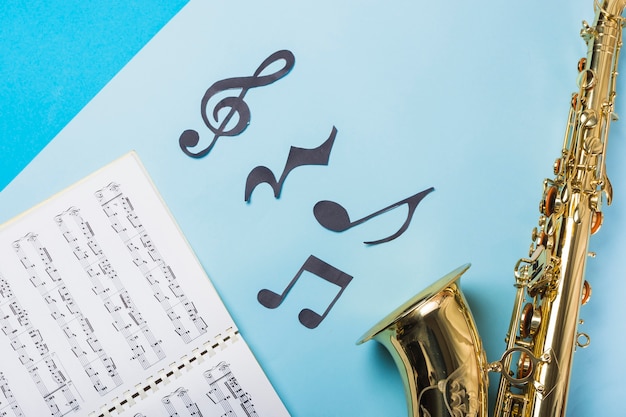 Musical notebook and golden saxophones on blue backdrop