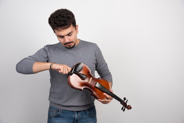 Musician checking and fixing the tune of his violin.