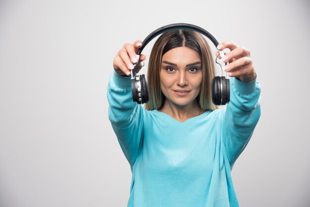 Musician girl holding black headphones.