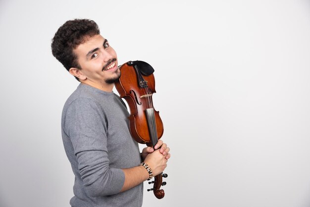 A musician holding his brown wooden violin and looks positive.