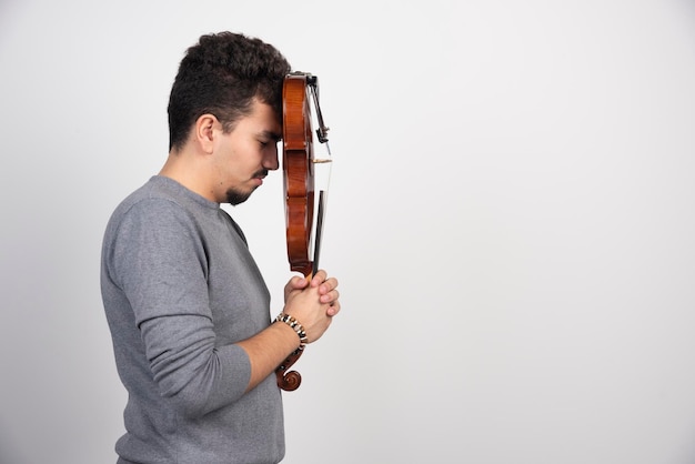 A musician holding his brown wooden violin and looks stressed.