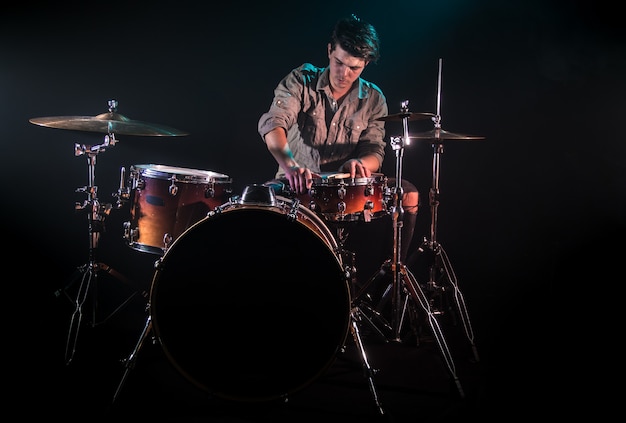 Бесплатное фото Музыкант играет на барабанах, черный фон и красивый мягкий свет, эмоциональная игра, музыкальная концепция