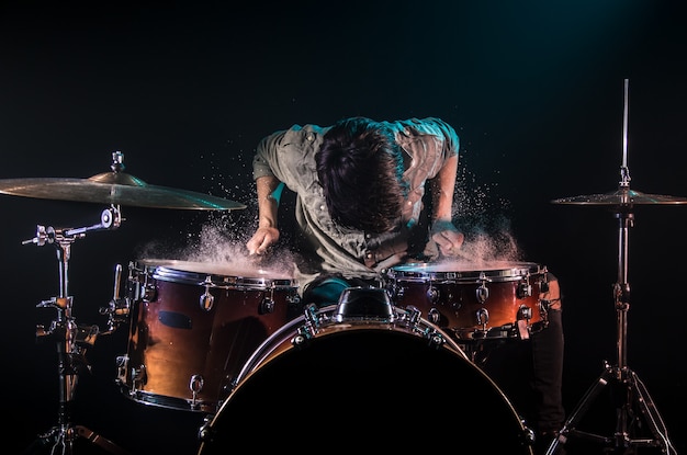 musician playing drums with splashes, black background with beautiful soft light, emotional play, music concept