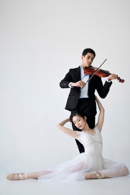 Free photo musician playing violin and ballerina posing