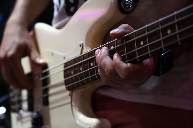 Musician playing white bass guitar close up.