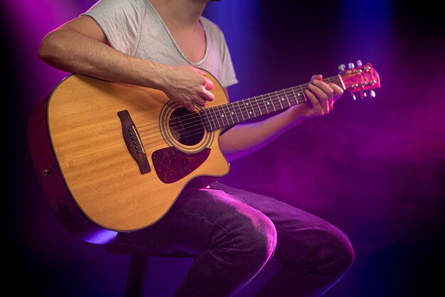 The musician plays an acoustic guitar.