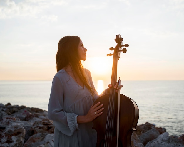 Musicista con violoncello all'aperto al tramonto