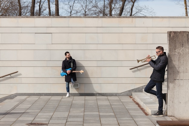 Musicians leaning on wall and playing