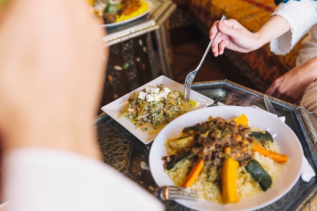 Muslim couple eating dish in restaurant