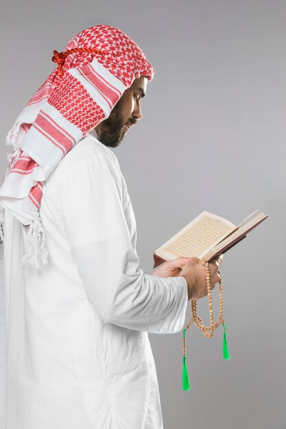 Muslim man reading from quran and holding praying beads