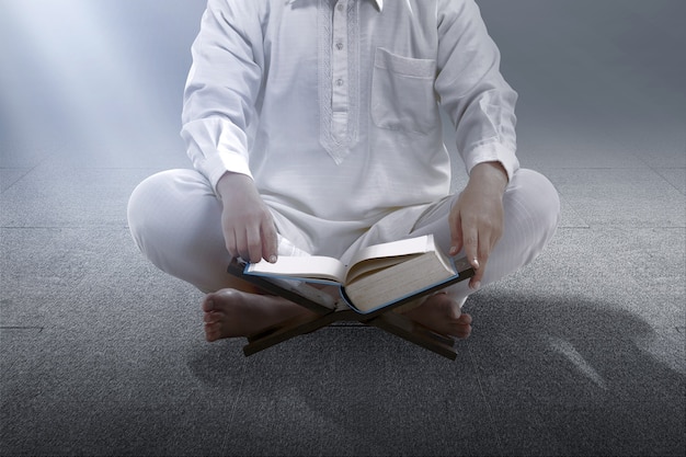 Muslim man sitting and reading the quran on the mosque
