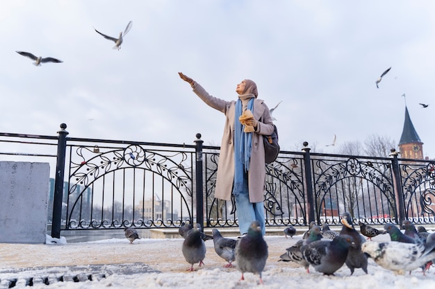 市内を旅行中に鳩に餌をやるイスラム教徒の女性