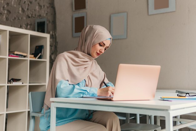 Muslim woman in hijab working in office room