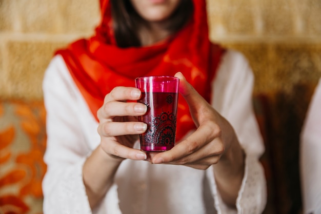 Muslim woman holding glass of tea