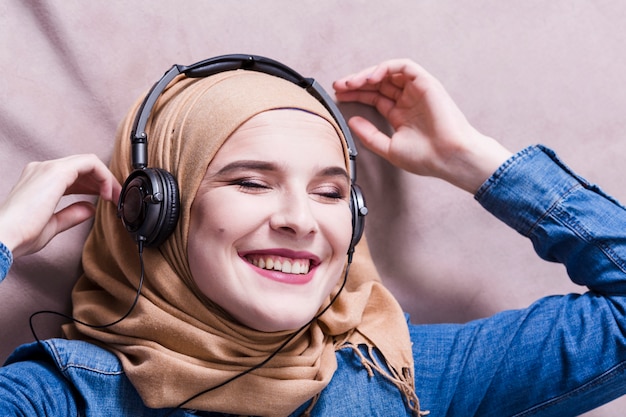 Muslim woman listening to music on headphones