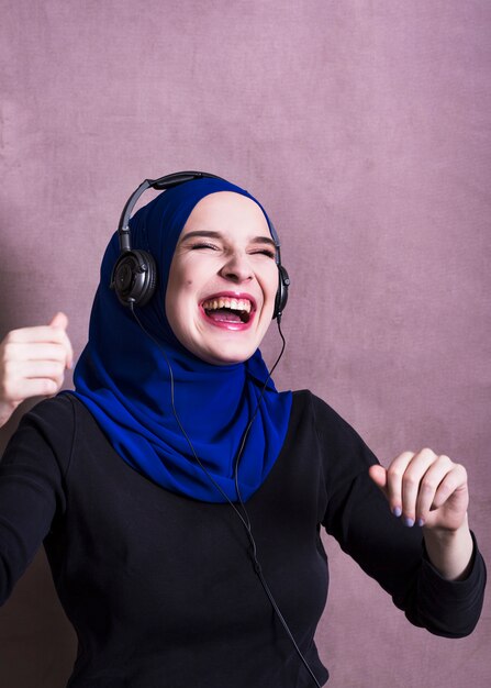 Muslim woman listening to music on headphones
