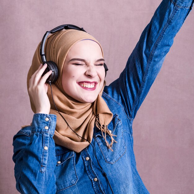 Muslim woman listening to music on headphones