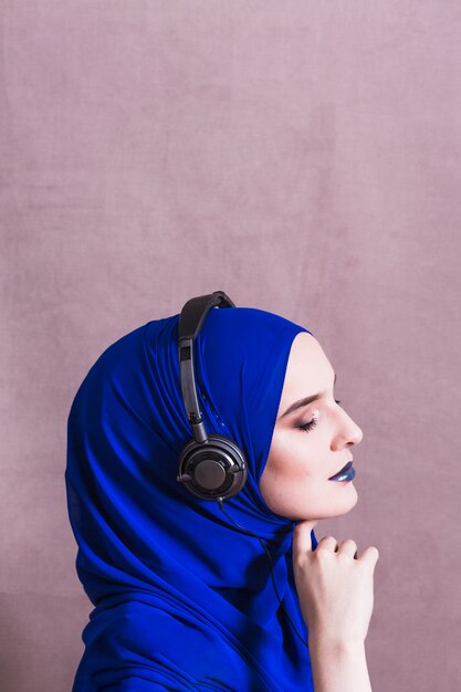 Muslim woman listening to music on headphones