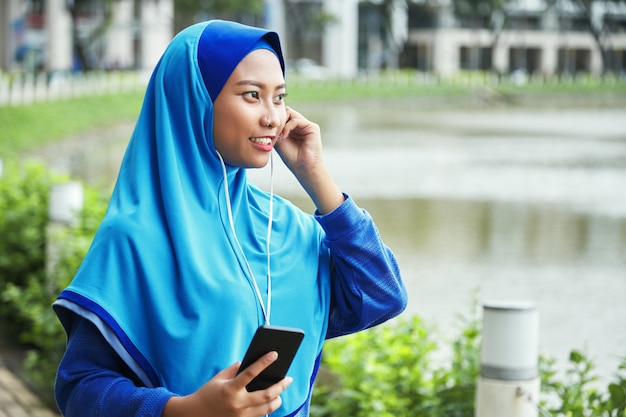 Мусульманская женщина слушает музыку на улице