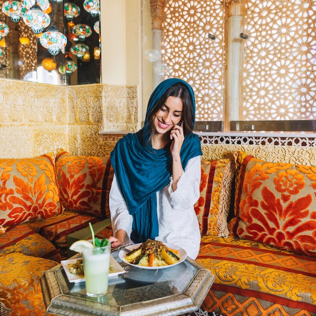 Free photo muslim woman making phone call in restaurant