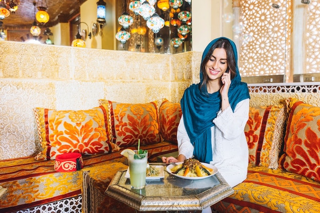 레스토랑에서 전화 통화하는 이슬람 여성