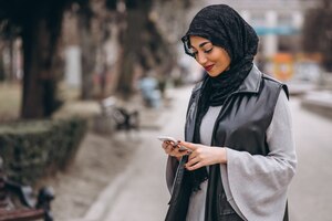 Donna musulmana che utilizza telefono fuori nella via